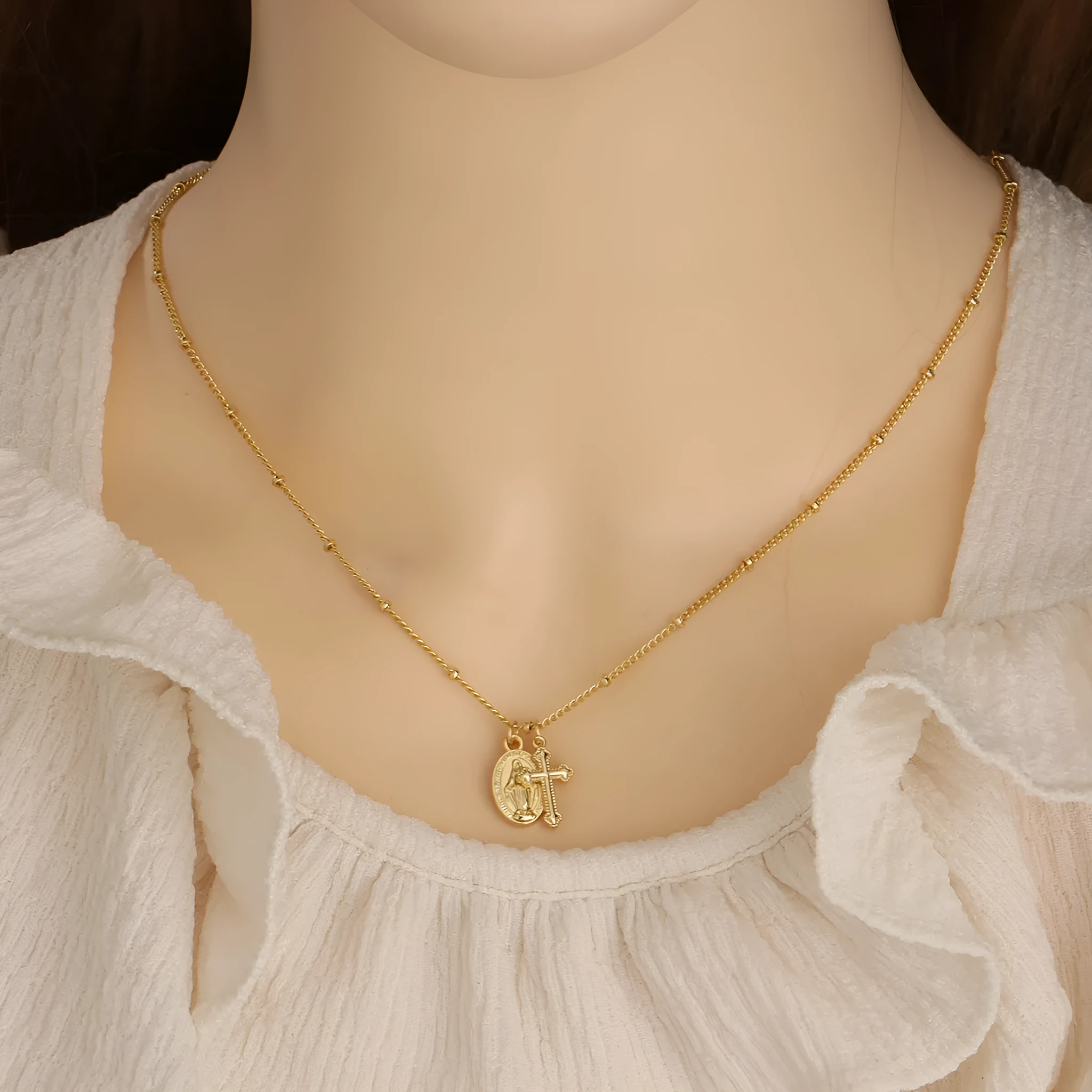 Gold coloured geometric cross necklace with a Virgin Mary ornament on a chain.