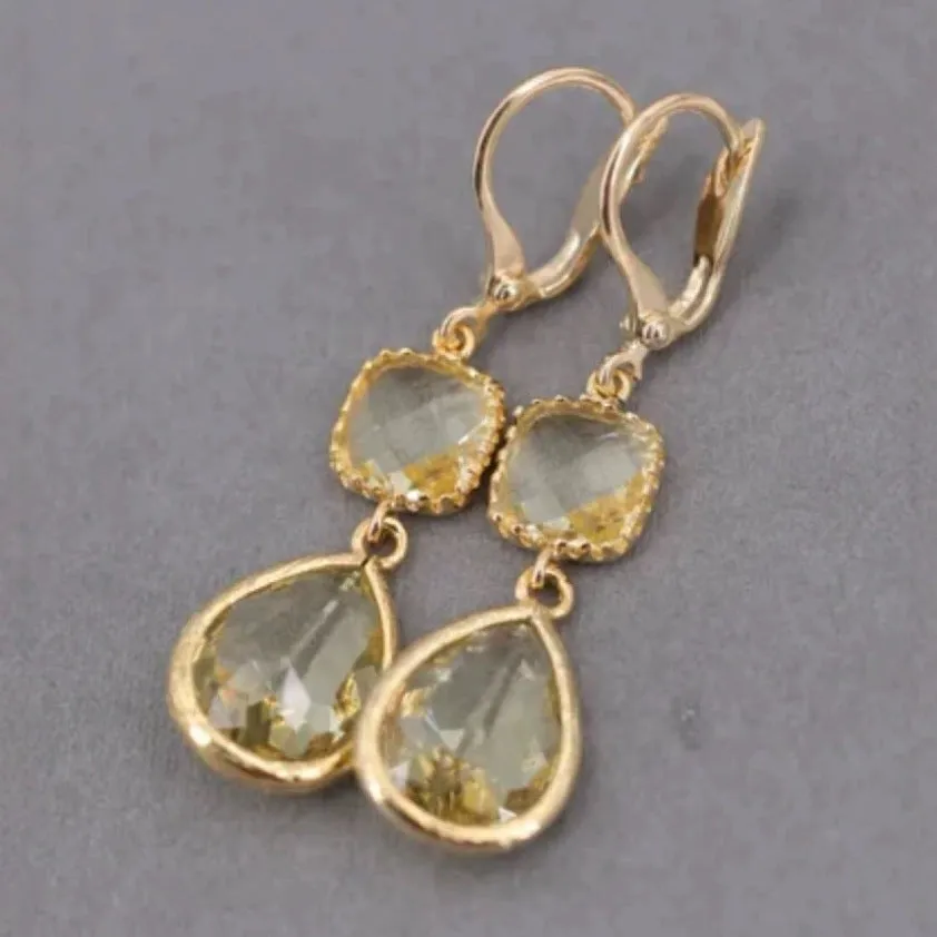 Gold geometric fringe earrings with water droplet design elements on white background