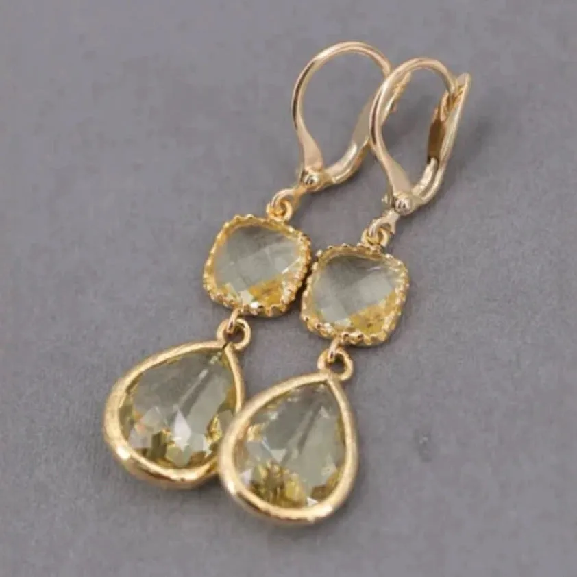 Gold geometric fringe earrings with water droplet design elements on white background