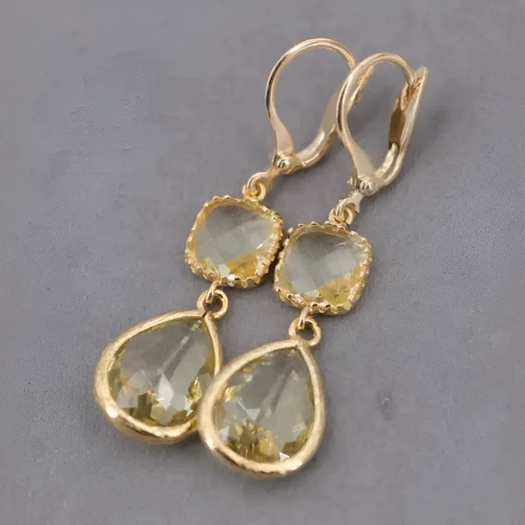 Gold geometric fringe earrings with water droplet design elements on white background