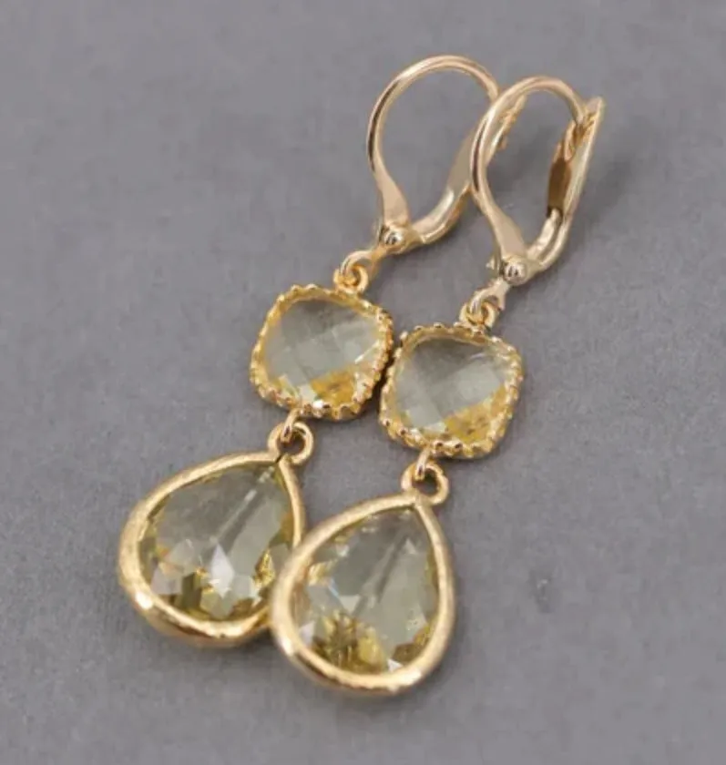Gold geometric fringe earrings with water droplet design elements on white background