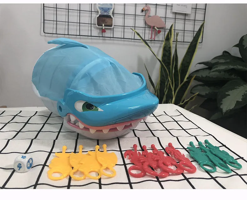 Great white shark tricky toy with small plastic fish inserted in its mouth on a tabletop