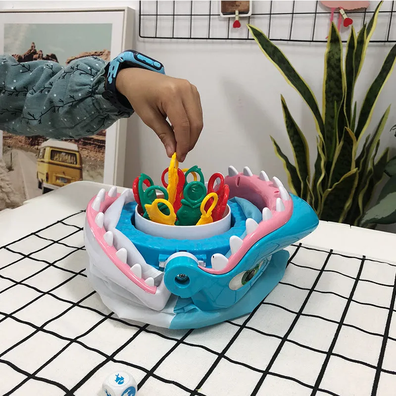 Great white shark tricky toy with small plastic fish inserted in its mouth on a tabletop