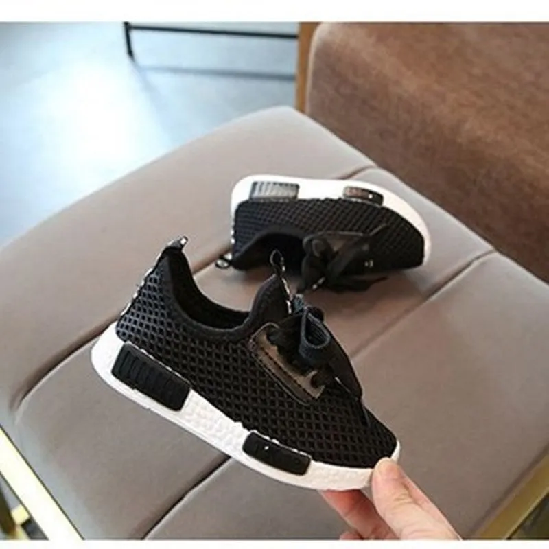 Mesh girls' primary school sneakers in white with rubber sole and front tie closure on a plain background