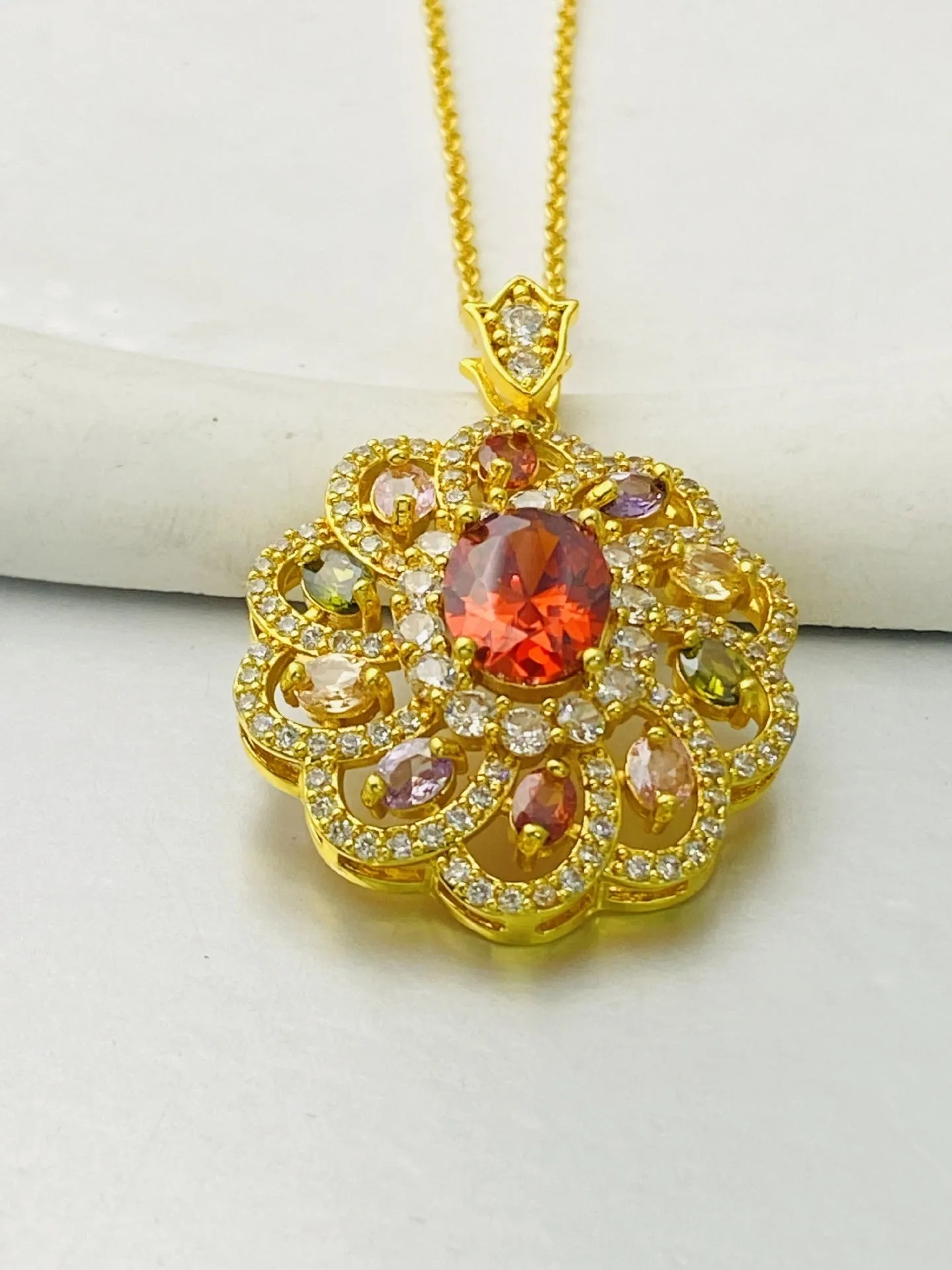 Close-up of a women's flower-shaped zircon pendant necklace in a gold electroplated finish.