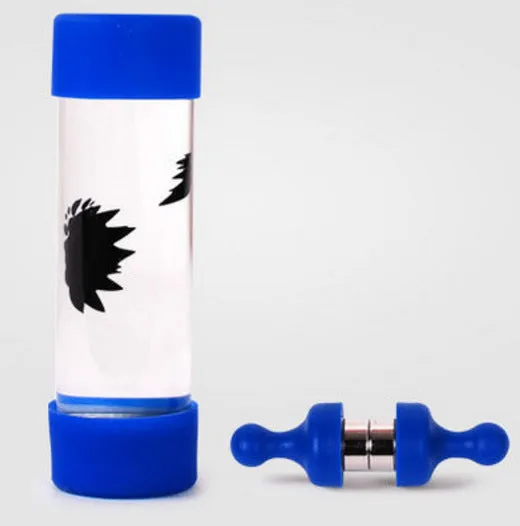 Magnetic fluid toy in a glass bottle with red ferrofluid and two black magnets on a white surface