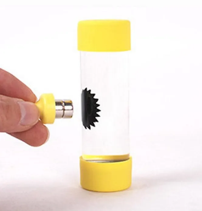 Magnetic fluid toy in a glass bottle with red ferrofluid and two black magnets on a white surface