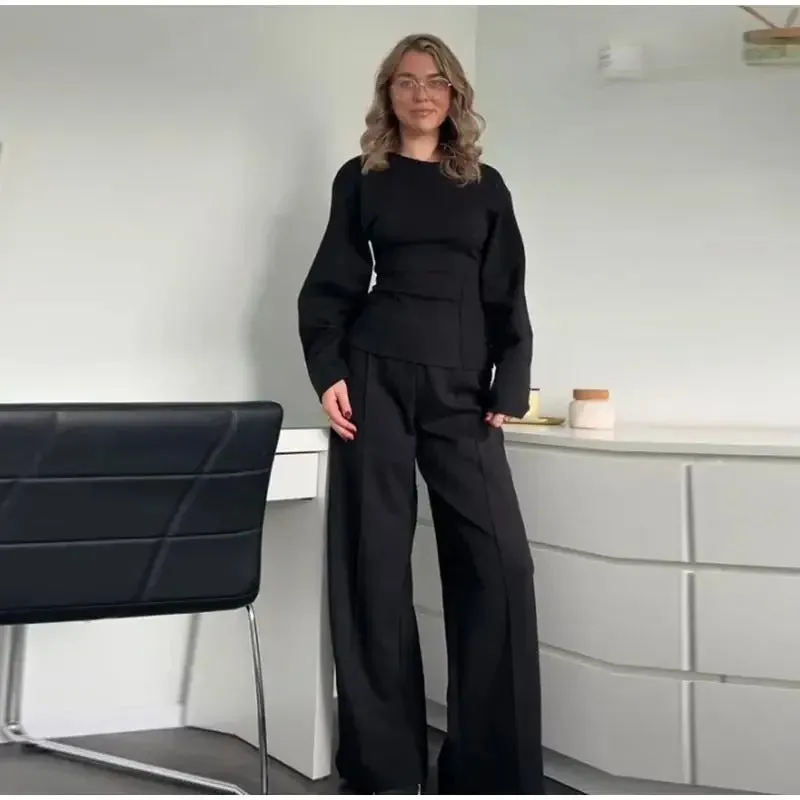 Women's black polar fleece suit set with long sleeve pleated top and wide leg trousers on a hanger.