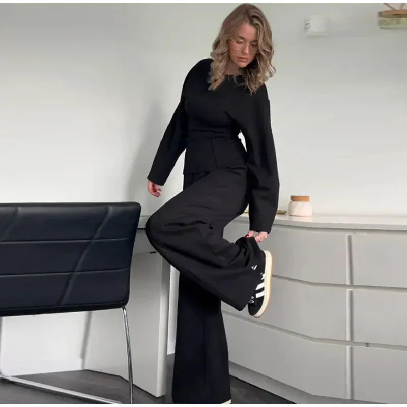 Women's black polar fleece suit set with long sleeve pleated top and wide leg trousers on a hanger.