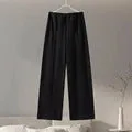 Women's black polar fleece suit set with long sleeve pleated top and wide leg trousers on a hanger.
