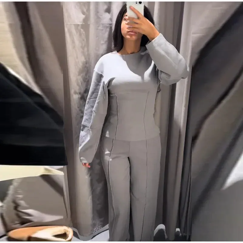 Women's black polar fleece suit set with long sleeve pleated top and wide leg trousers on a hanger.