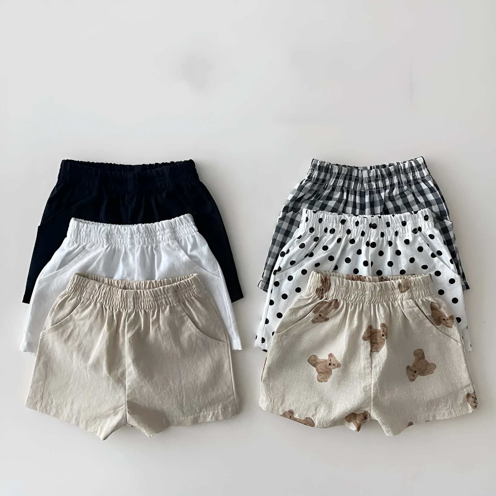 Baby loose thin cotton and linen shorts in black with elastic waist, side view on white background
