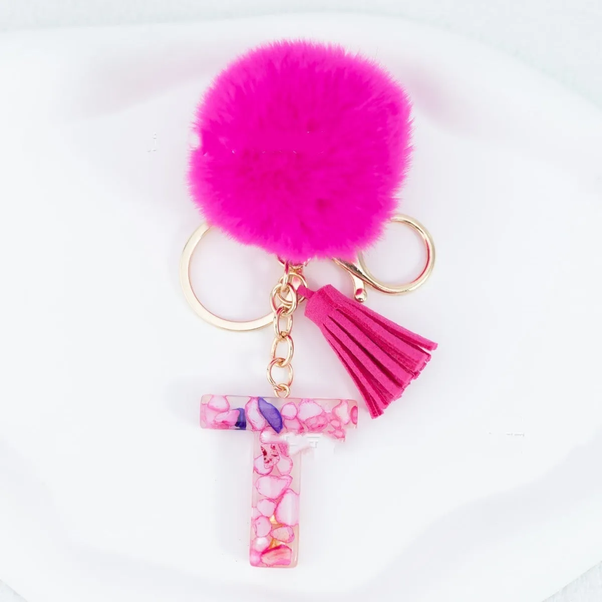 Rose red stone keychain with English letter B, fur ball and tassel on a white background