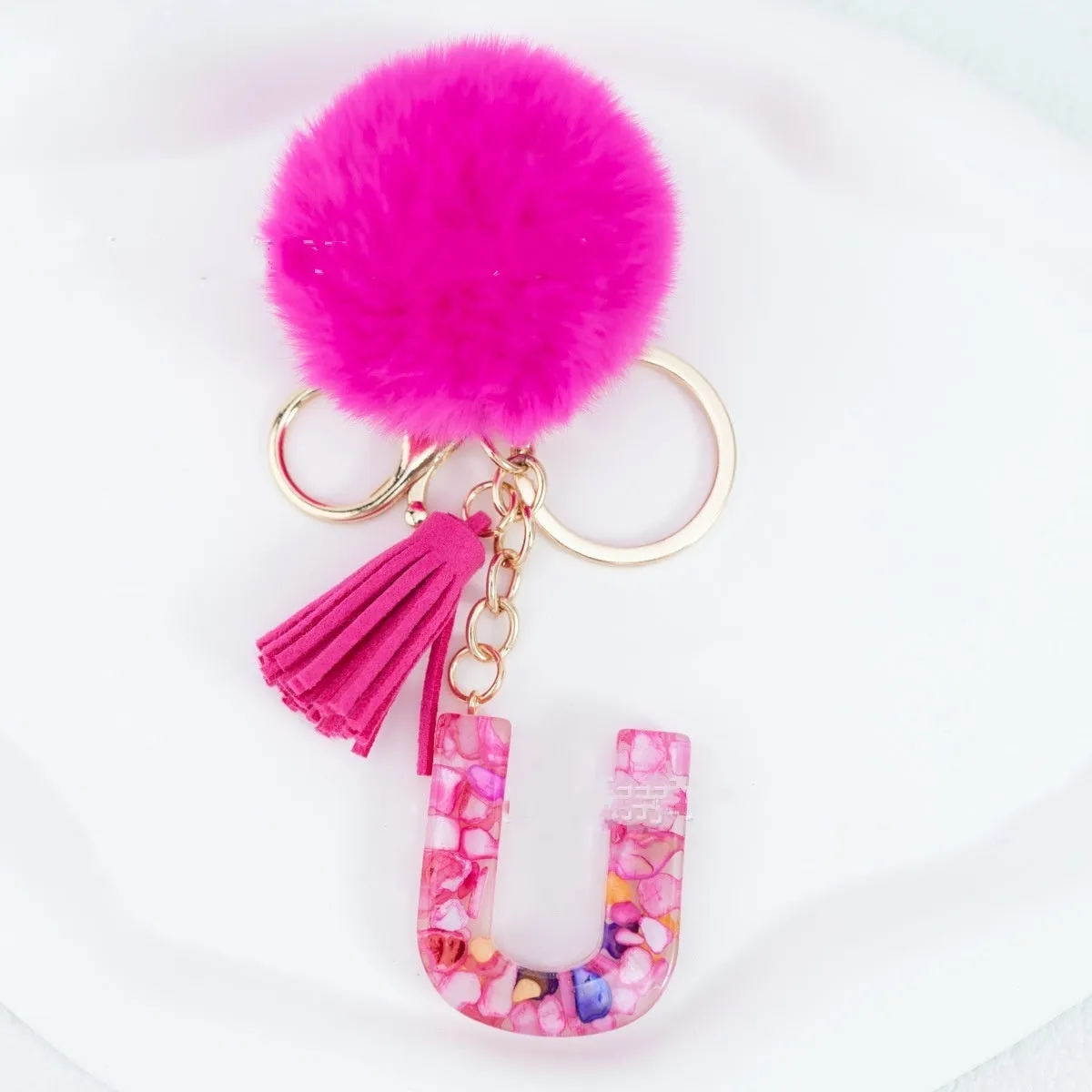 Rose red stone keychain with English letter B, fur ball and tassel on a white background