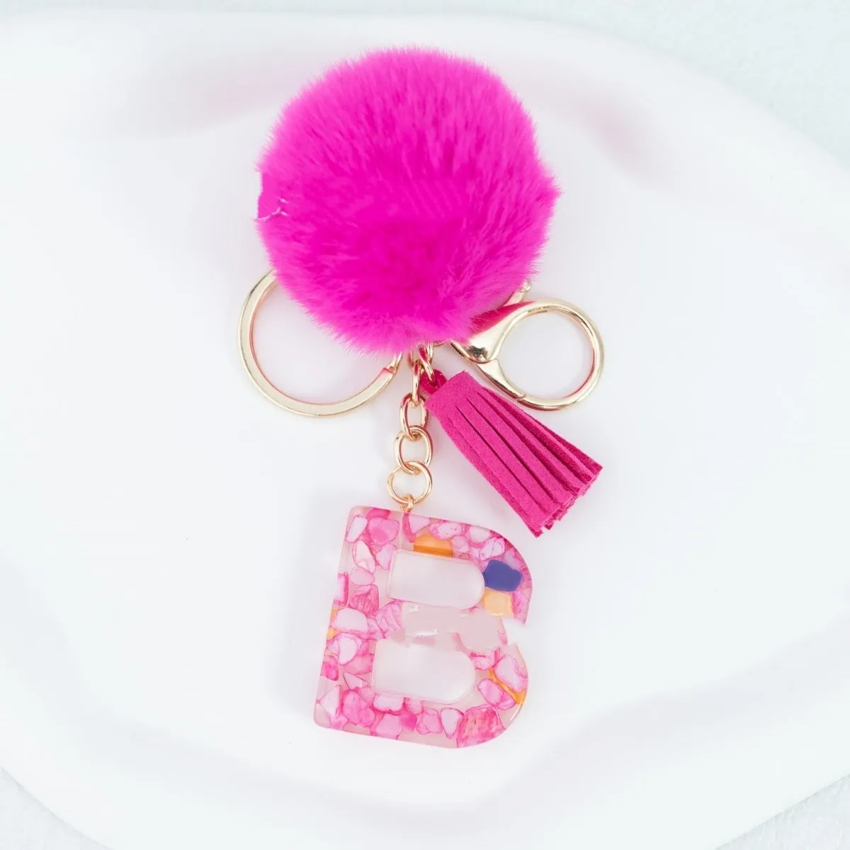 Rose red stone keychain with English letter B, fur ball and tassel on a white background