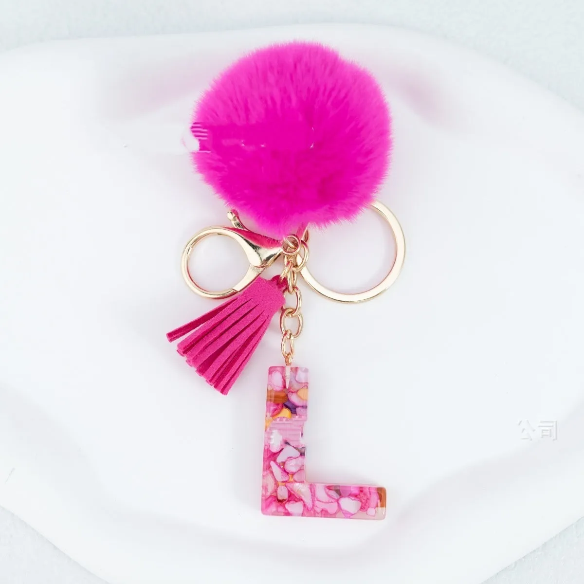 Rose red stone keychain with English letter B, fur ball and tassel on a white background