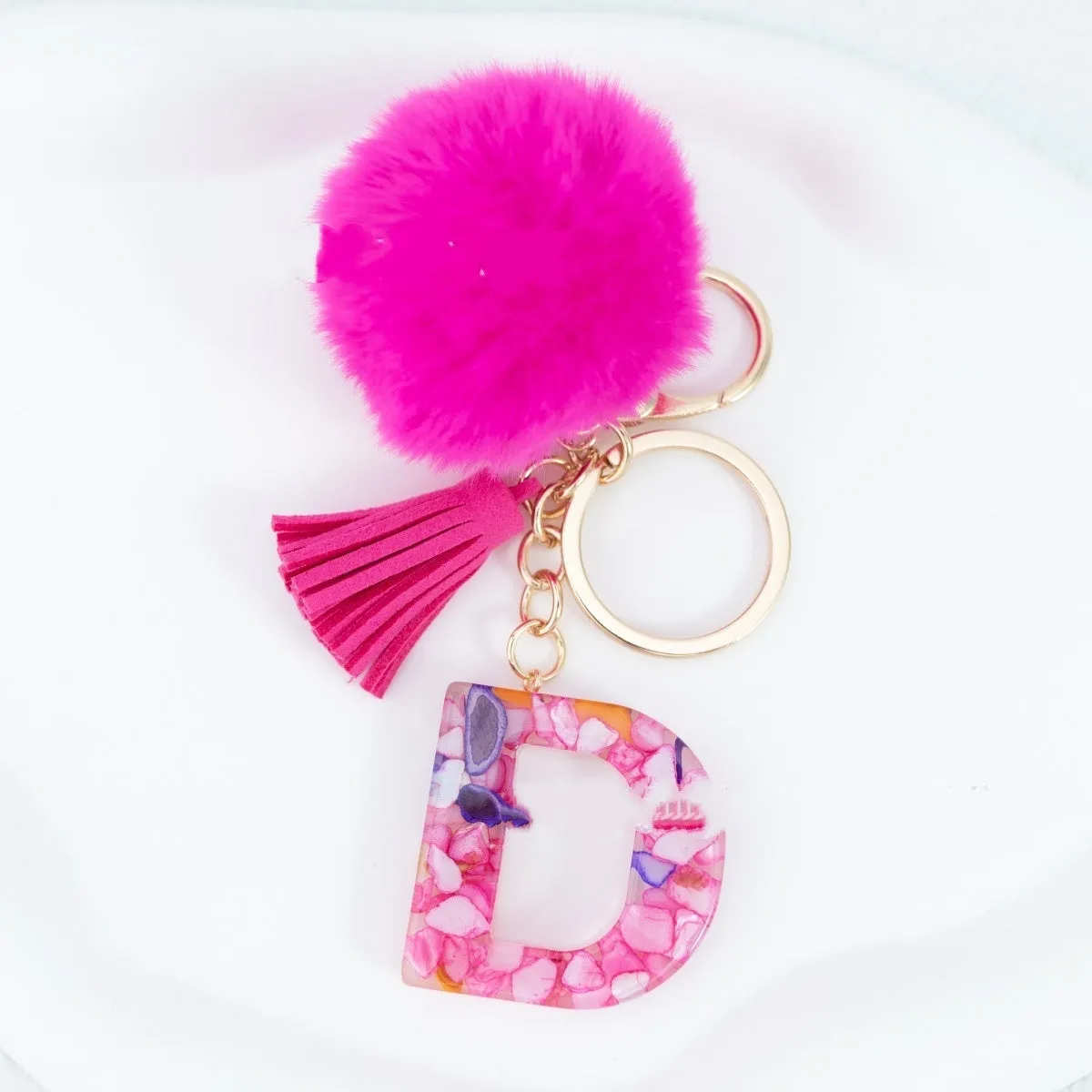 Rose red stone keychain with English letter B, fur ball and tassel on a white background