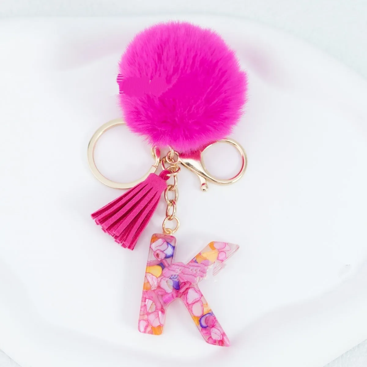 Rose red stone keychain with English letter B, fur ball and tassel on a white background