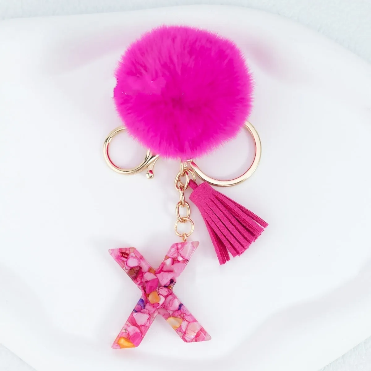 Rose red stone keychain with English letter B, fur ball and tassel on a white background