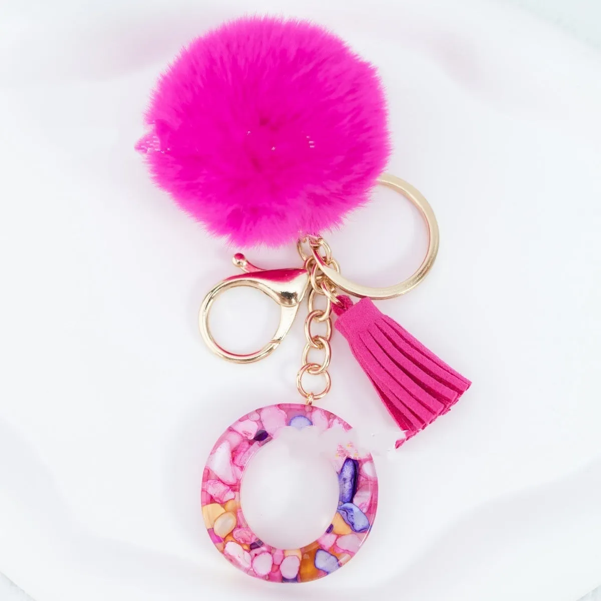 Rose red stone keychain with English letter B, fur ball and tassel on a white background