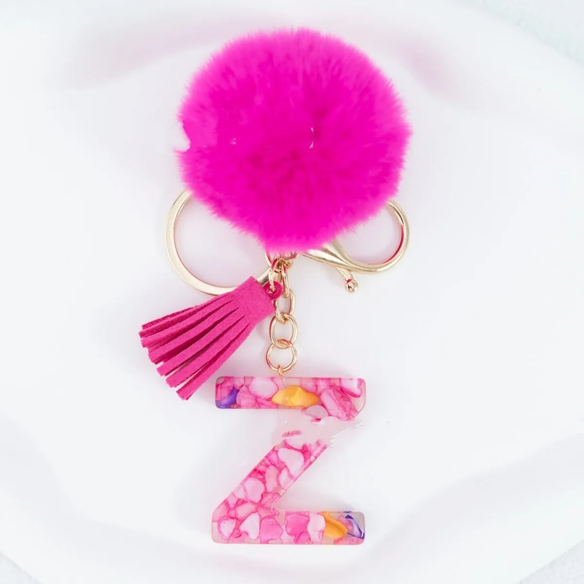 Rose red stone keychain with English letter B, fur ball and tassel on a white background