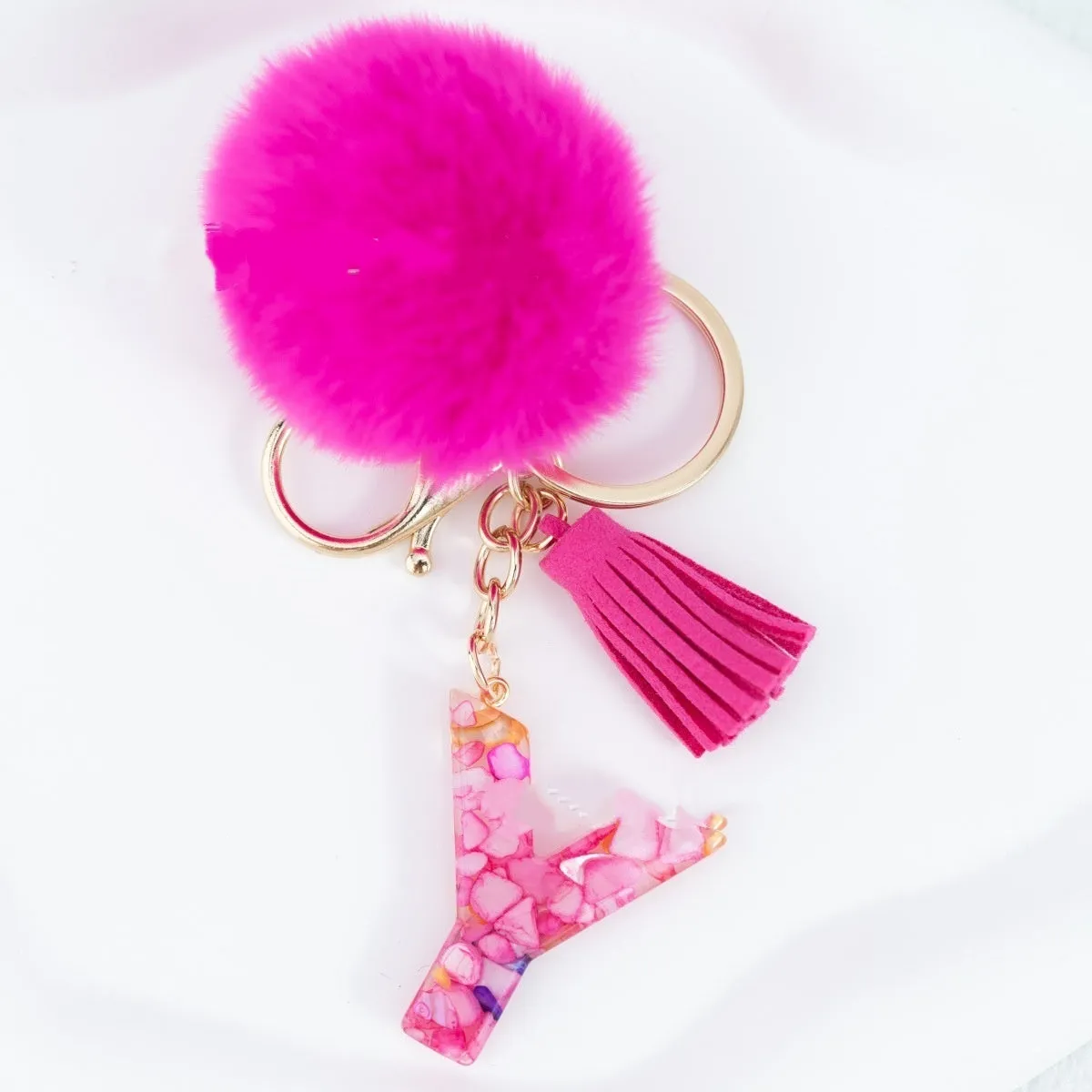 Rose red stone keychain with English letter B, fur ball and tassel on a white background