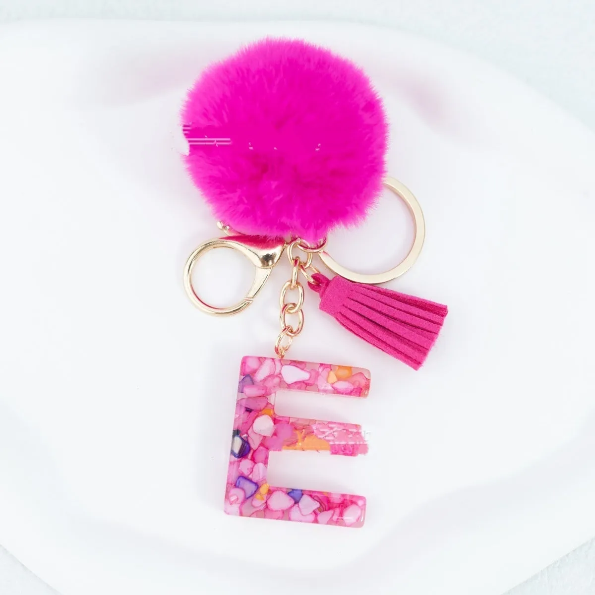 Rose red stone keychain with English letter B, fur ball and tassel on a white background