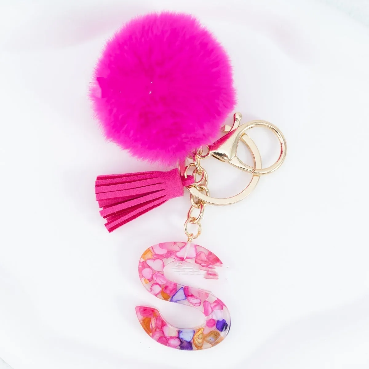 Rose red stone keychain with English letter B, fur ball and tassel on a white background