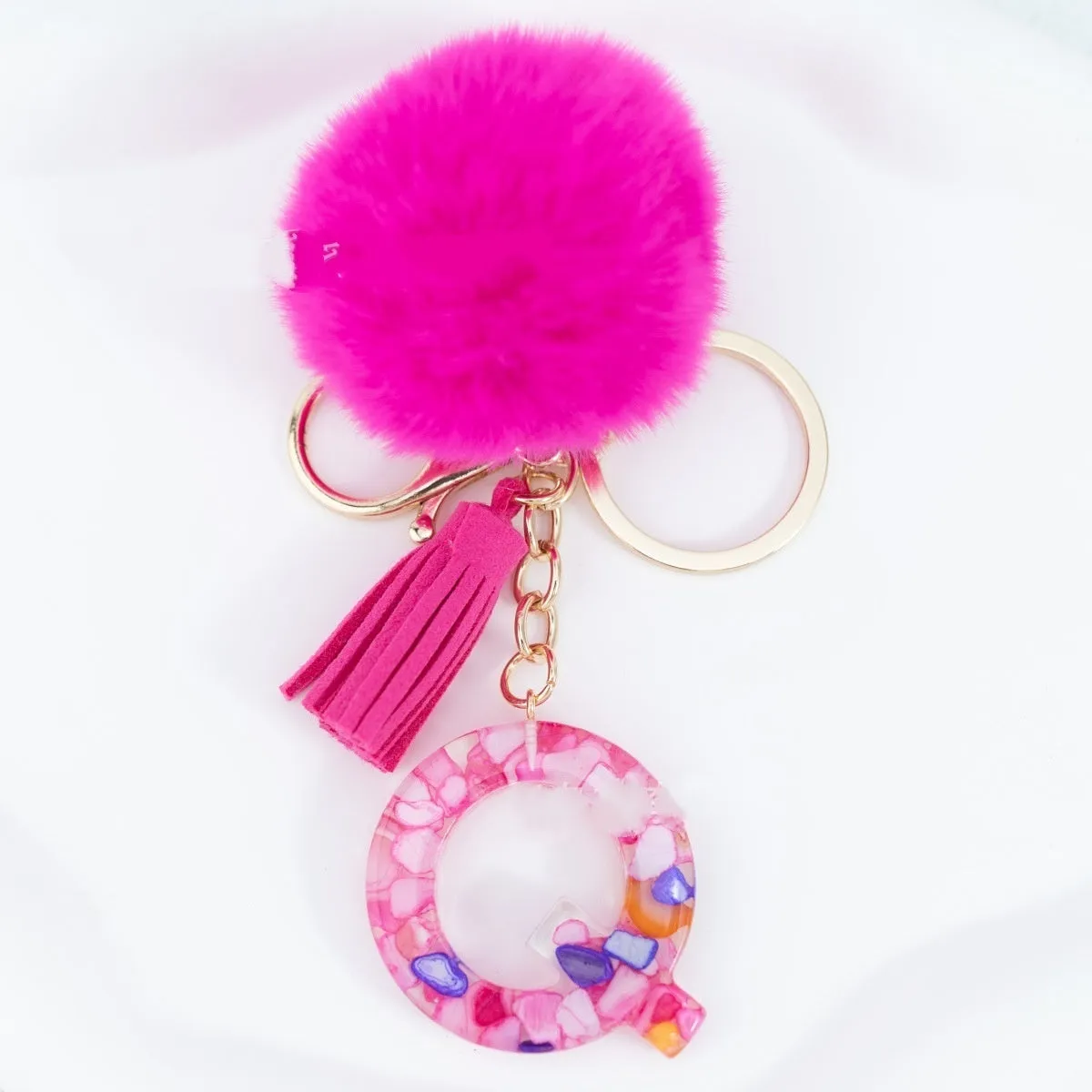 Rose red stone keychain with English letter B, fur ball and tassel on a white background