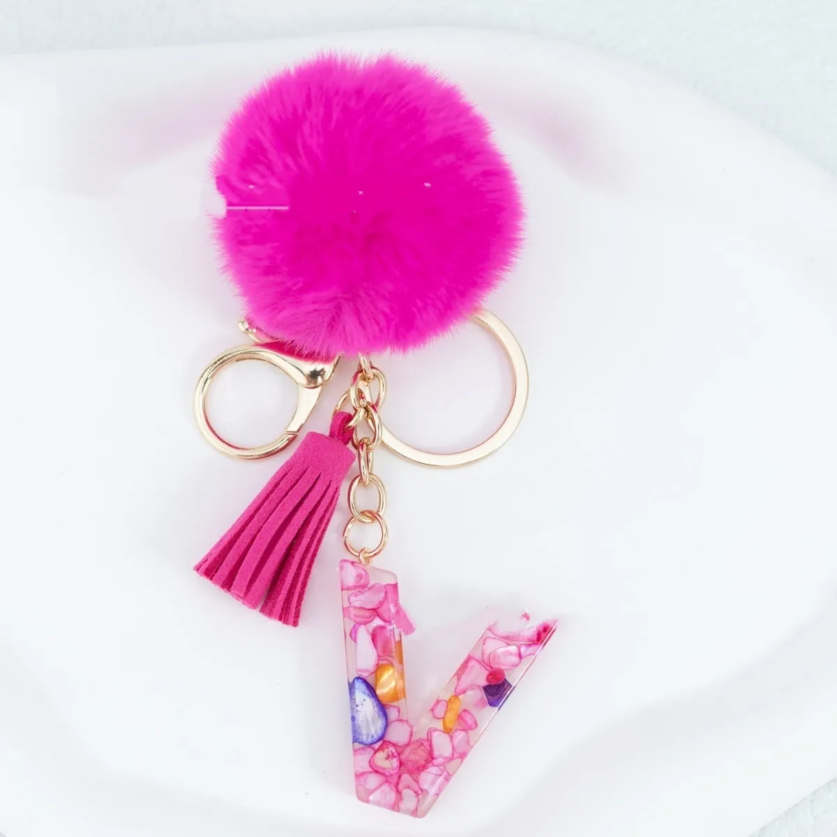 Rose red stone keychain with English letter B, fur ball and tassel on a white background
