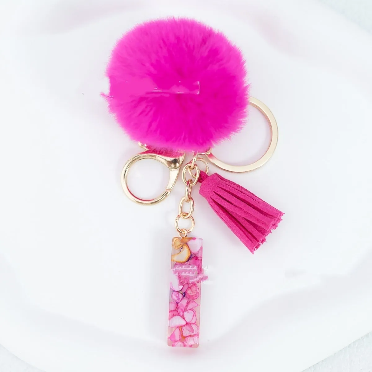 Rose red stone keychain with English letter B, fur ball and tassel on a white background