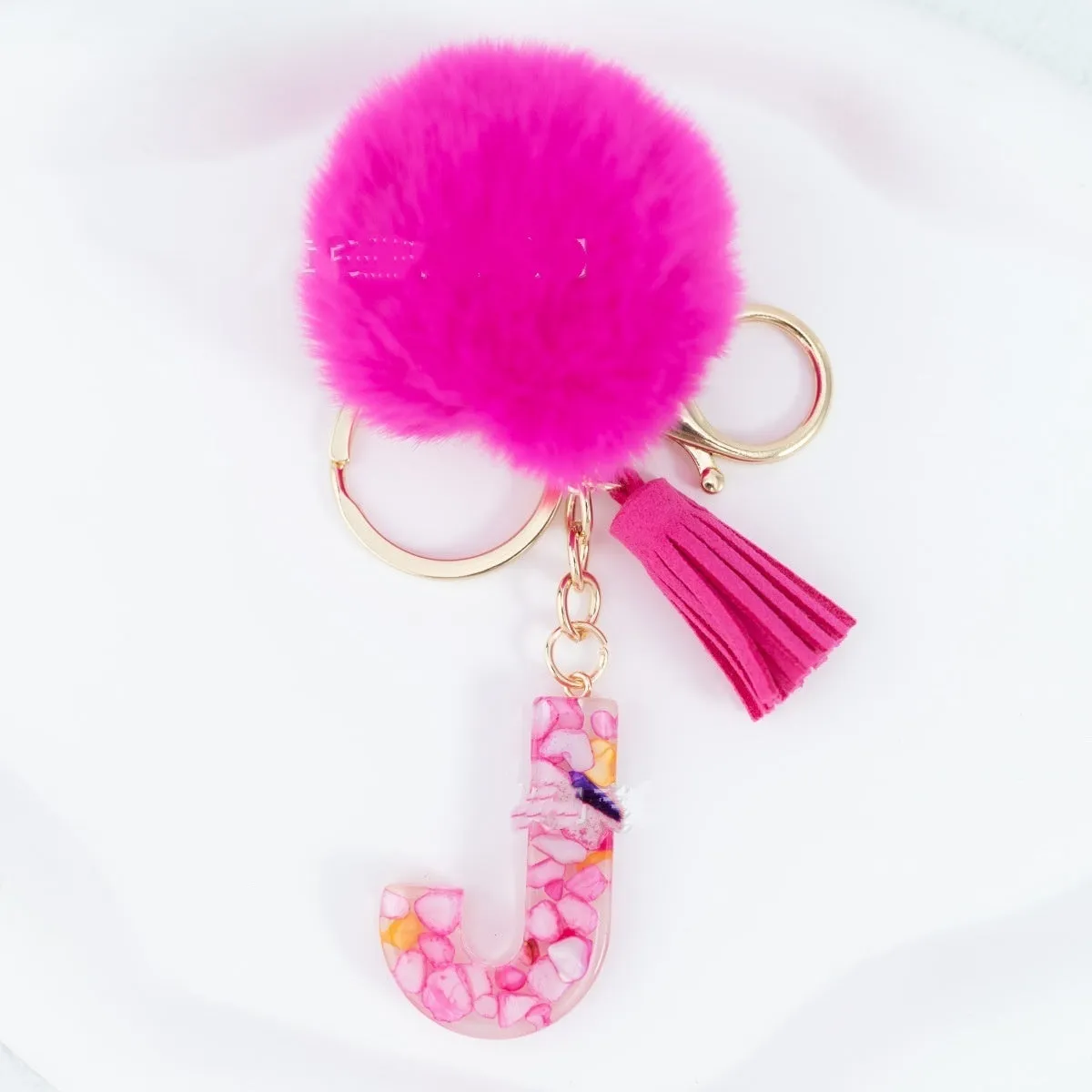 Rose red stone keychain with English letter B, fur ball and tassel on a white background