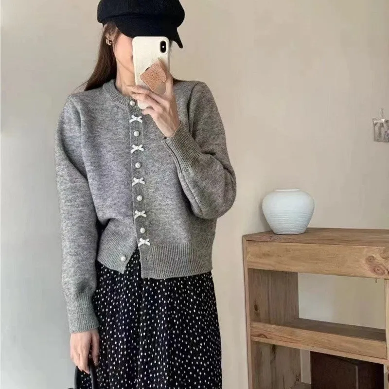 Women's solid colour cardigan sweater with bow and pearl buttons, shown in light yellow.