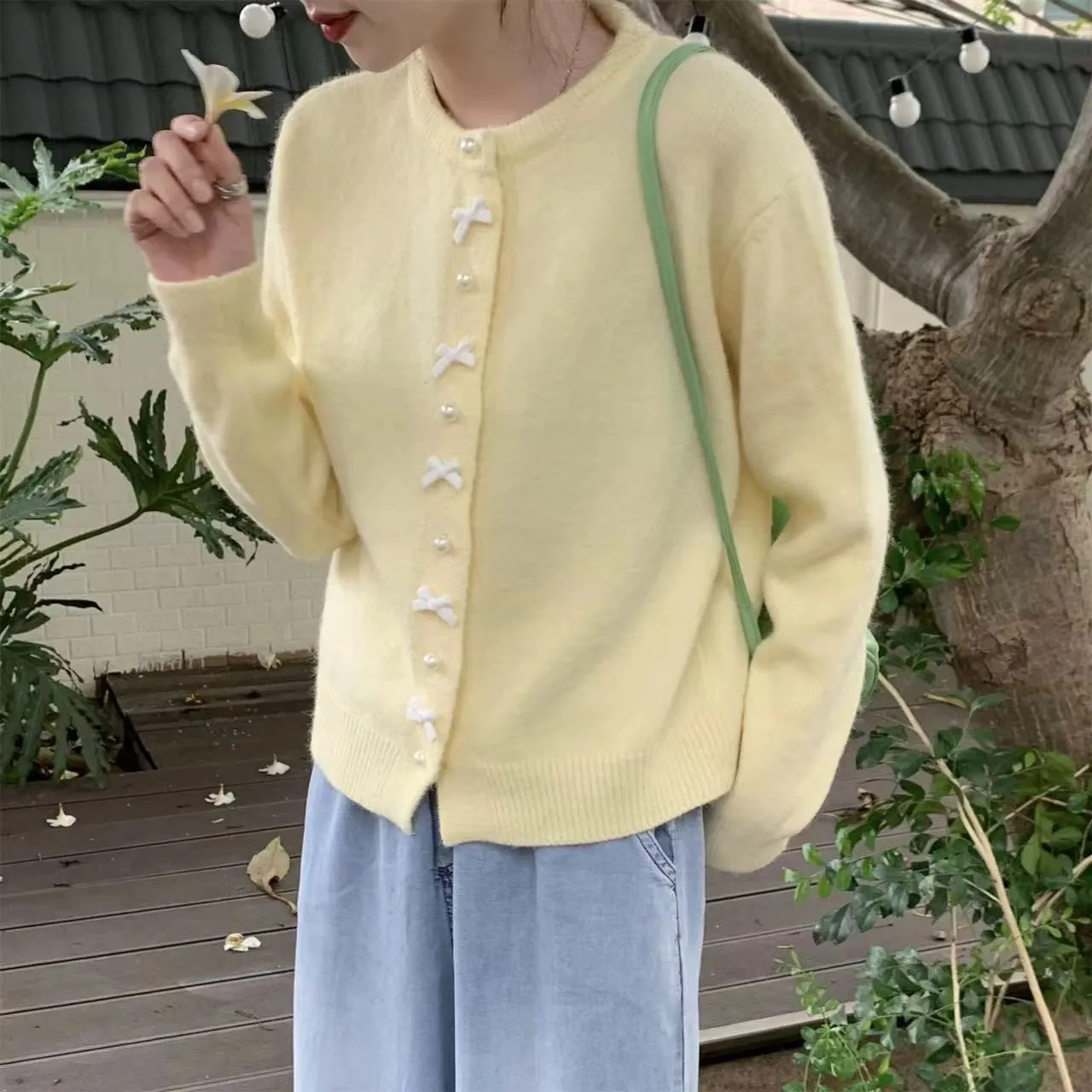 Women's solid colour cardigan sweater with bow and pearl buttons, shown in light yellow.