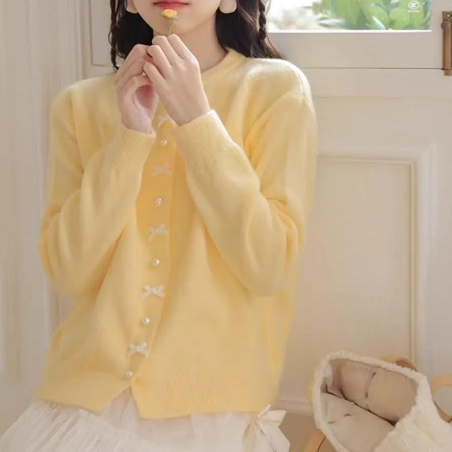Women's solid colour cardigan sweater with bow and pearl buttons, shown in light yellow.