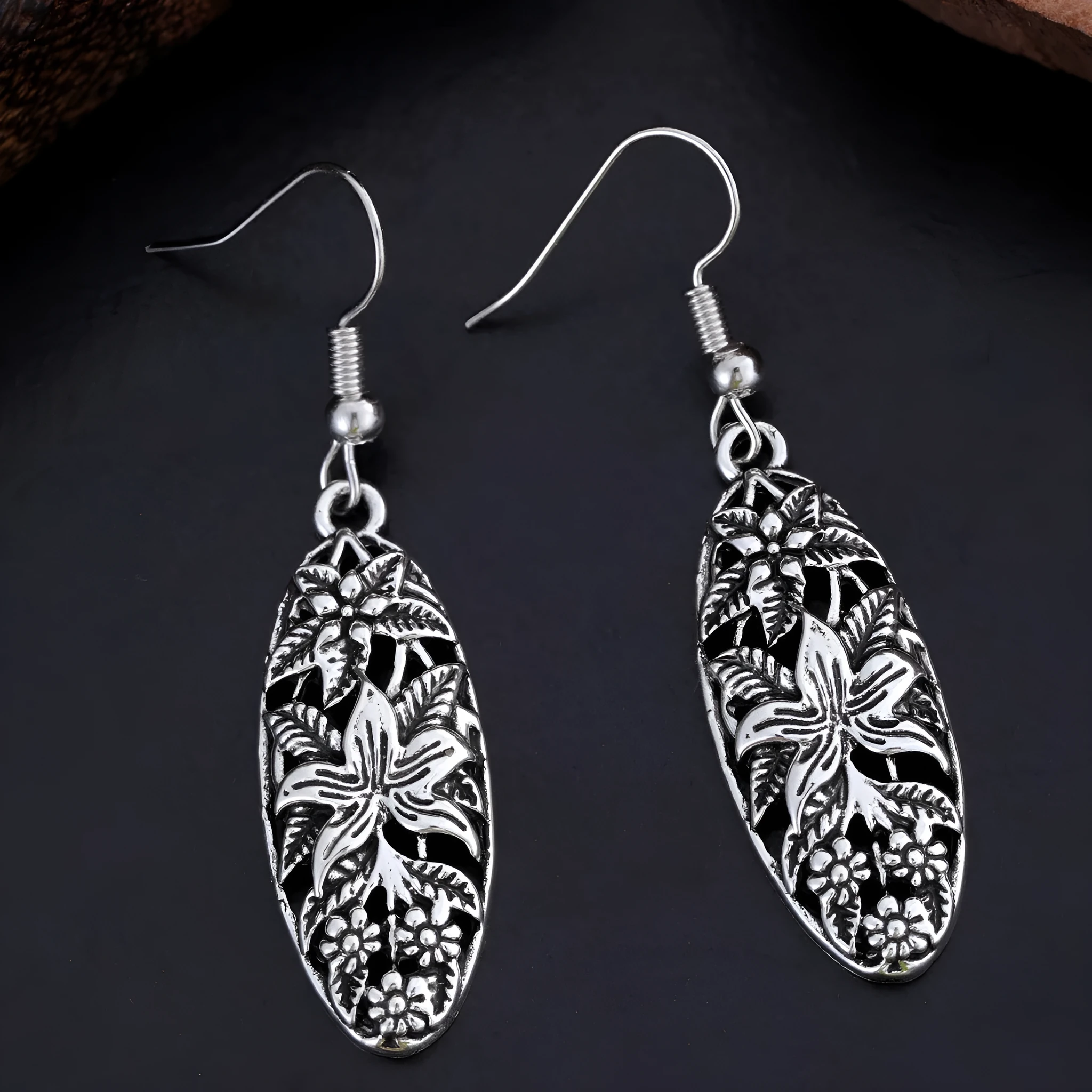 Pair of silver-tone retro hollowed out long water droplet drop earrings on light background
