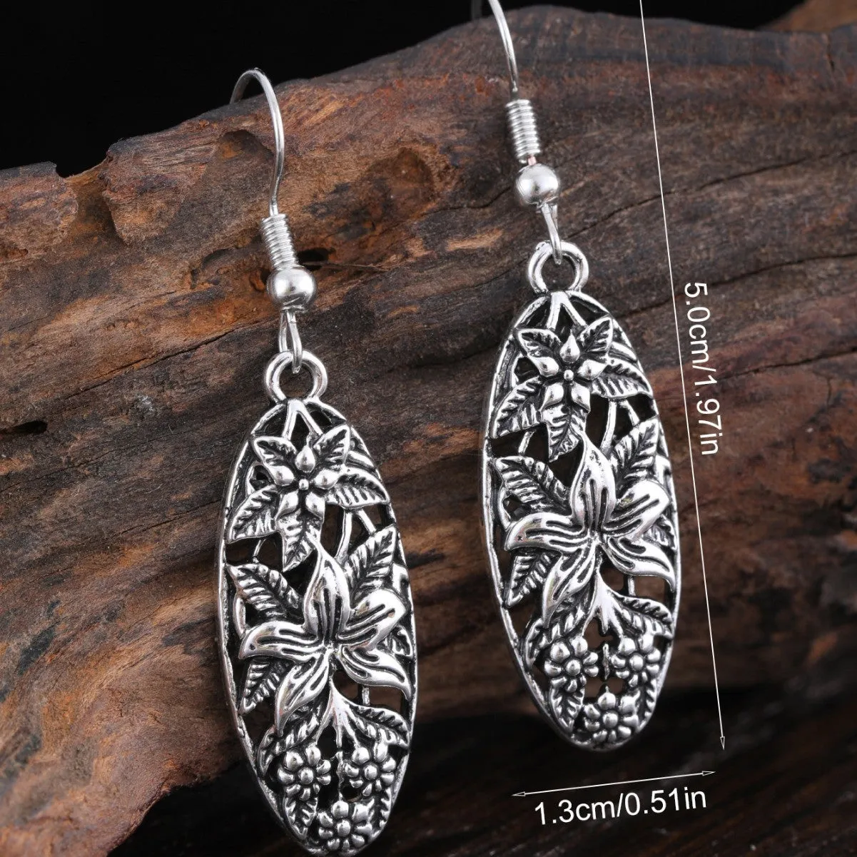 Pair of silver-tone retro hollowed out long water droplet drop earrings on light background