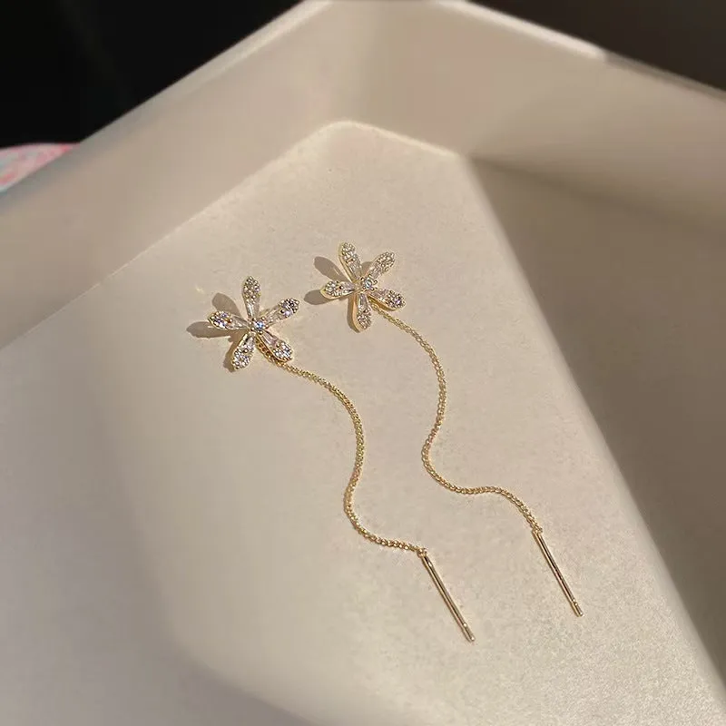 Long gold drop earrings for women with metal construction and secure fastening on white background