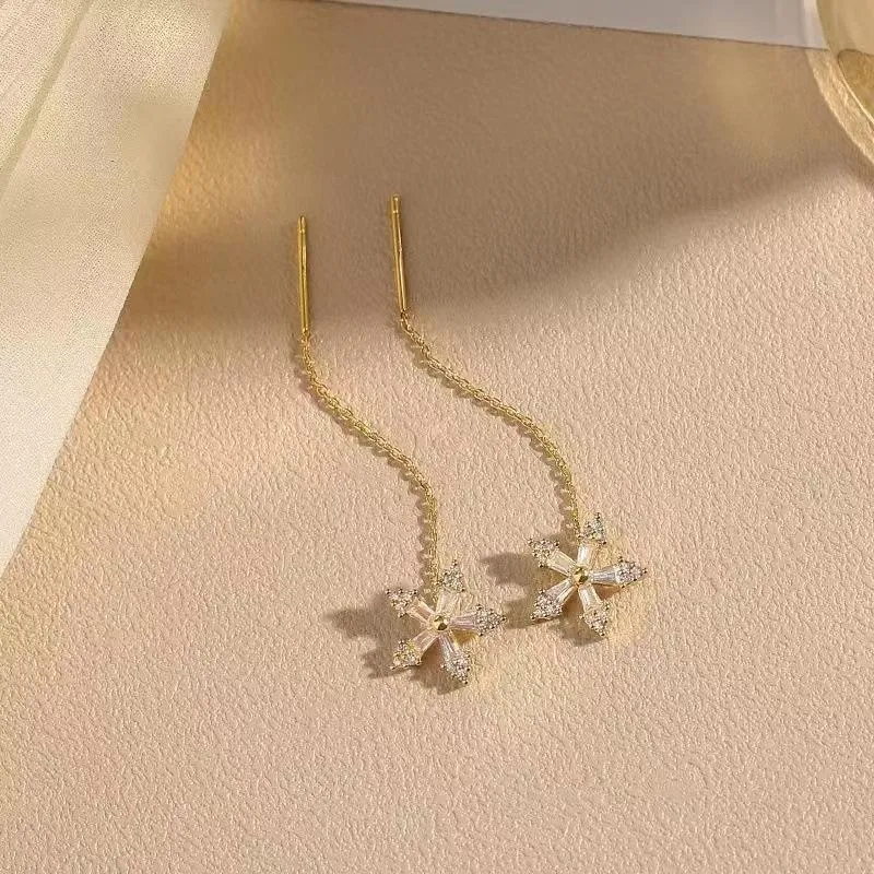 Long gold drop earrings for women with metal construction and secure fastening on white background