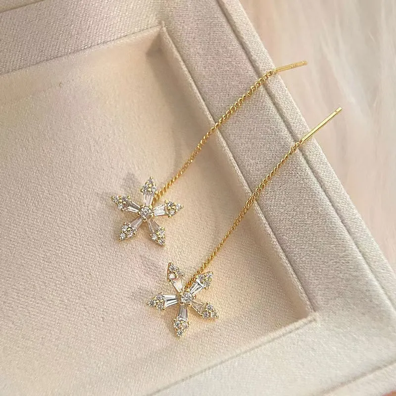 Long gold drop earrings for women with metal construction and secure fastening on white background