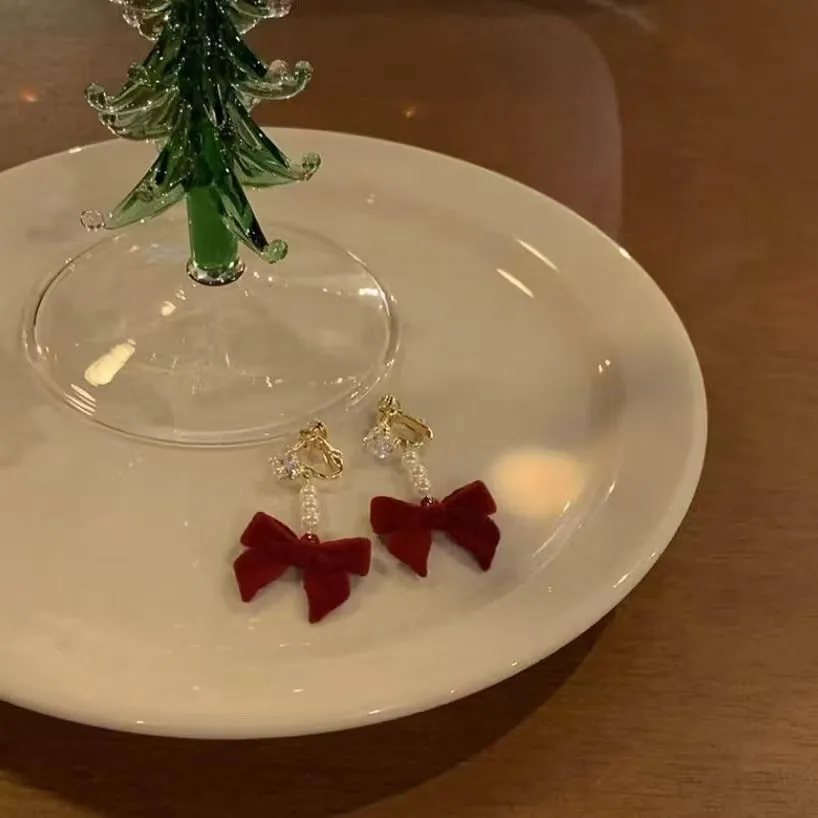 Red velvet bow clip-on earrings with pearl centre on white background