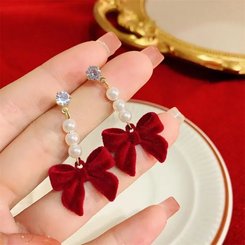 Red velvet bow clip-on earrings with pearl centre on white background