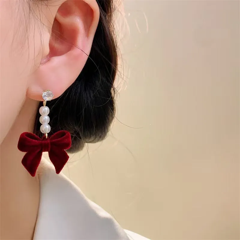 Red velvet bow clip-on earrings with pearl centre on white background