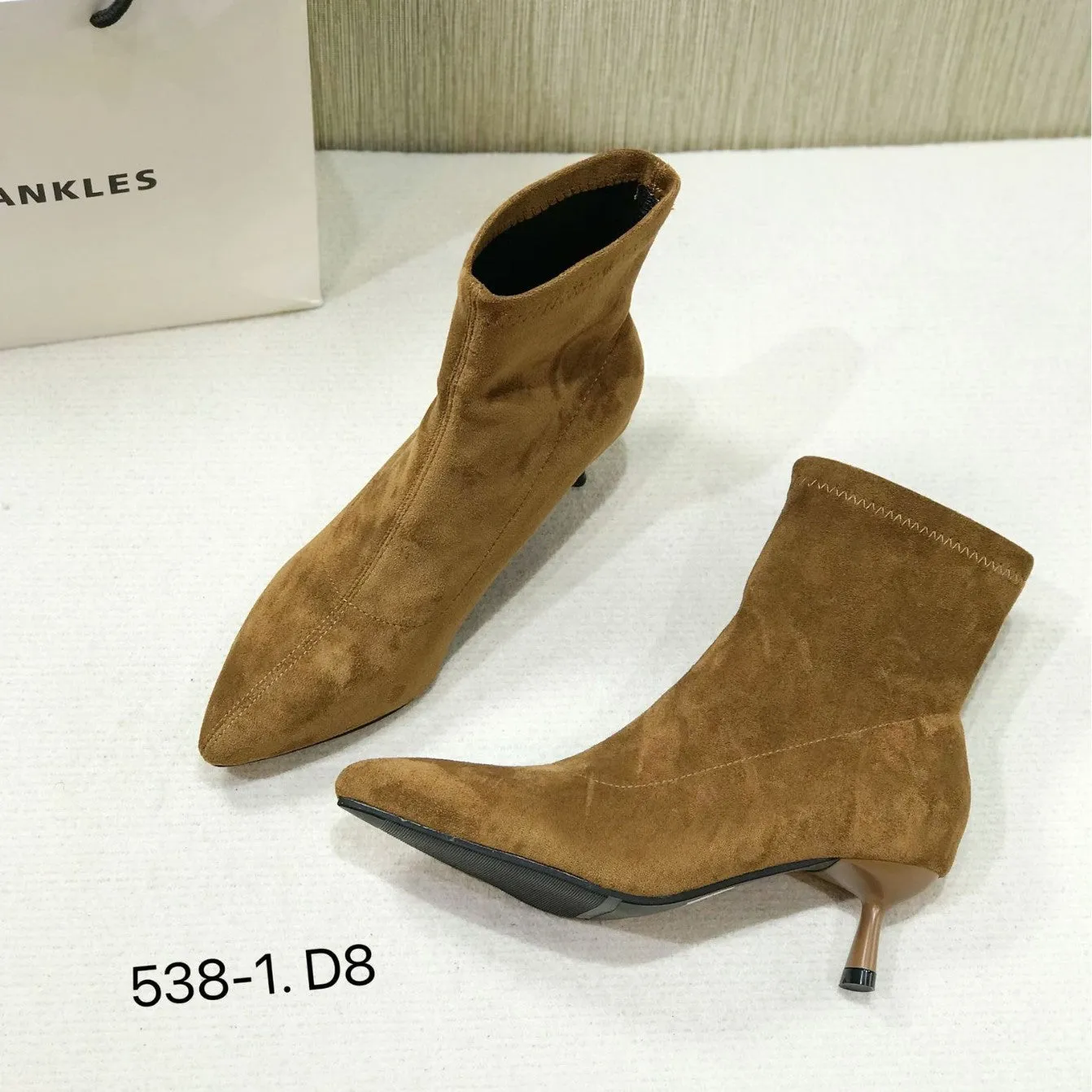 Black pointed toe women's ankle boot with a stiletto heel on a plain background.