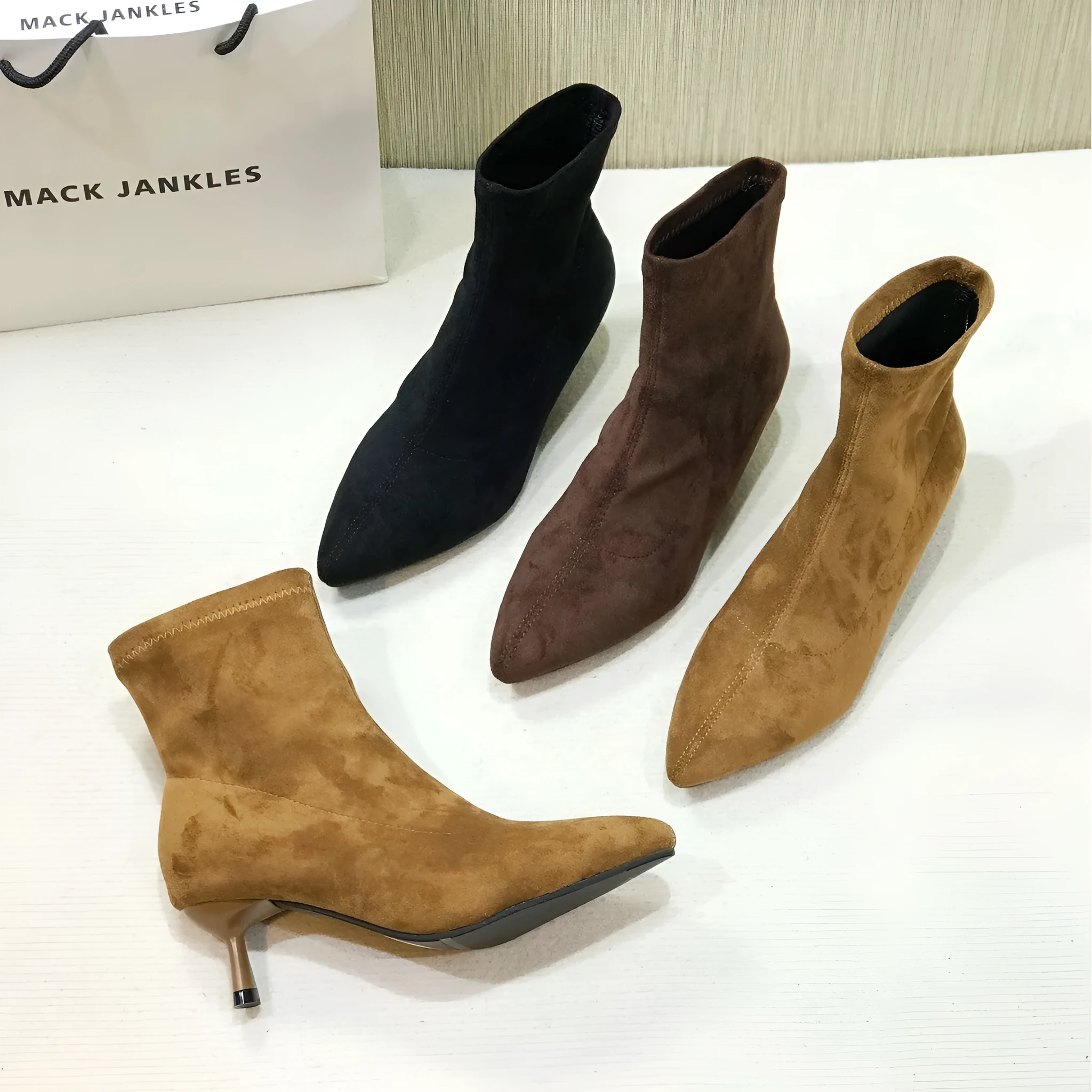 Black pointed toe women's ankle boot with a stiletto heel on a plain background.