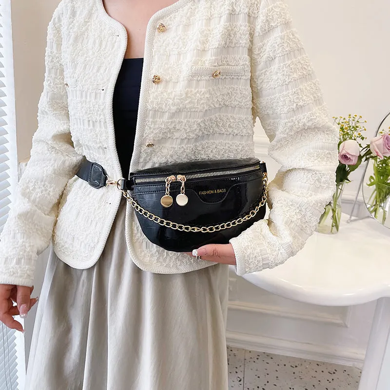 Shiny hard-shell PU chest bag with wide shoulder strap, chain detail, and internal pockets in silver colour