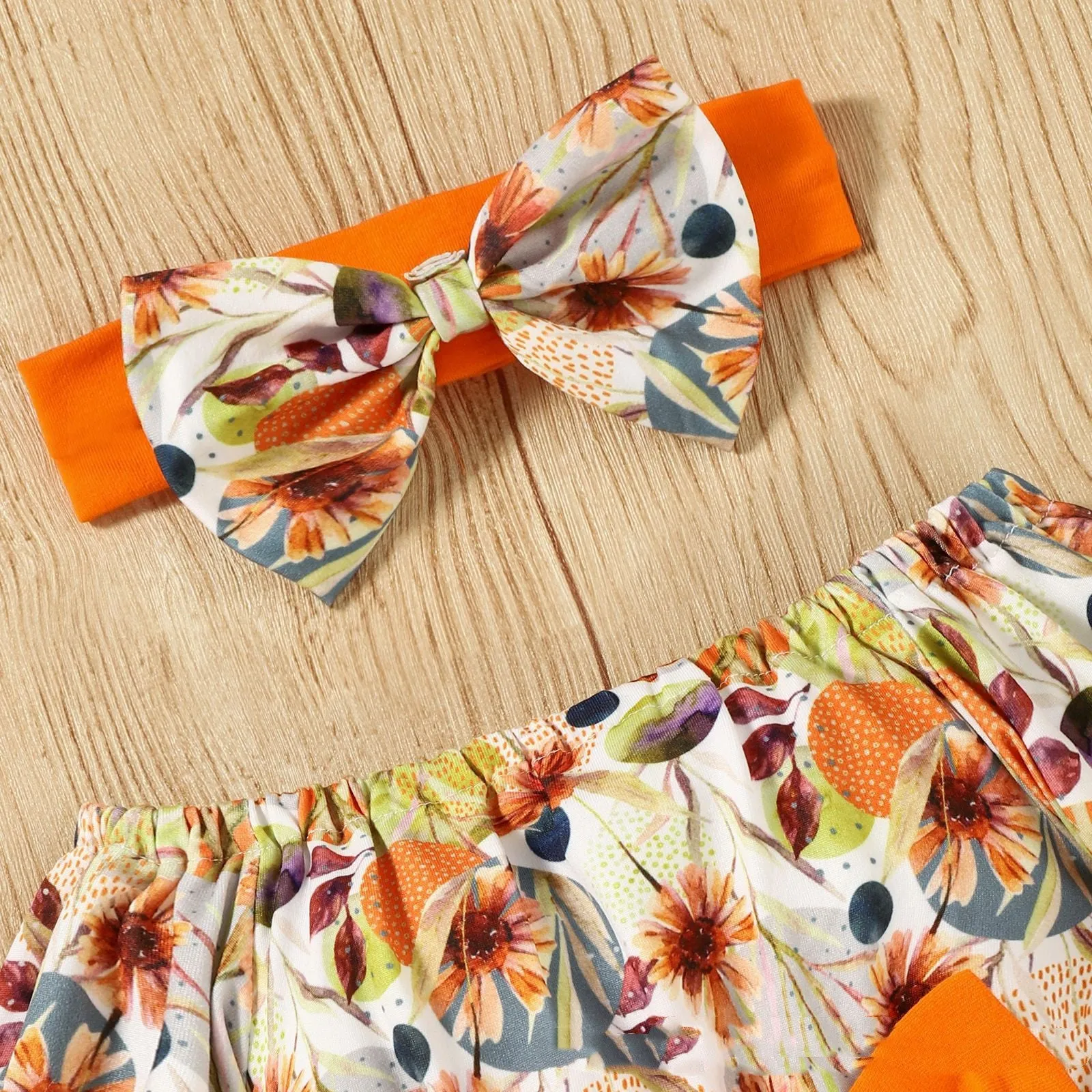 Baby wearing a floral flare sleeve romper band set with matching headband on a neutral background