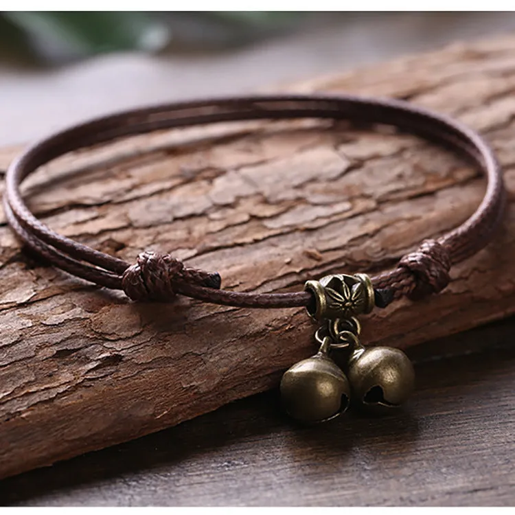 Black nylon rope dog collar with a small brass bell, shown adjusted on a model.