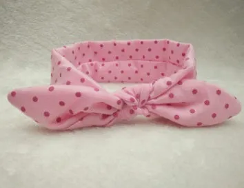 Set of 9 cotton jersey baby headbands in various colours with rabbit ears on white background
