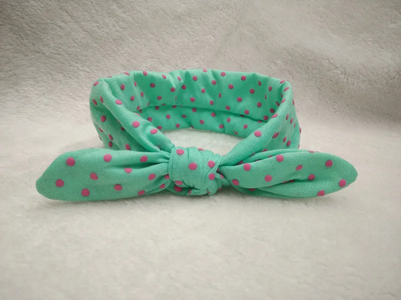 Set of 9 cotton jersey baby headbands in various colours with rabbit ears on white background